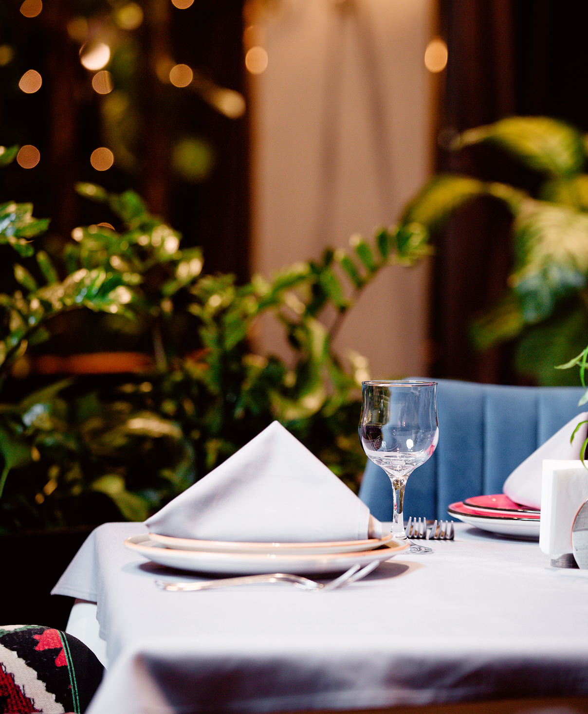 Restaurant table dressed with white linen, glassware and greenery